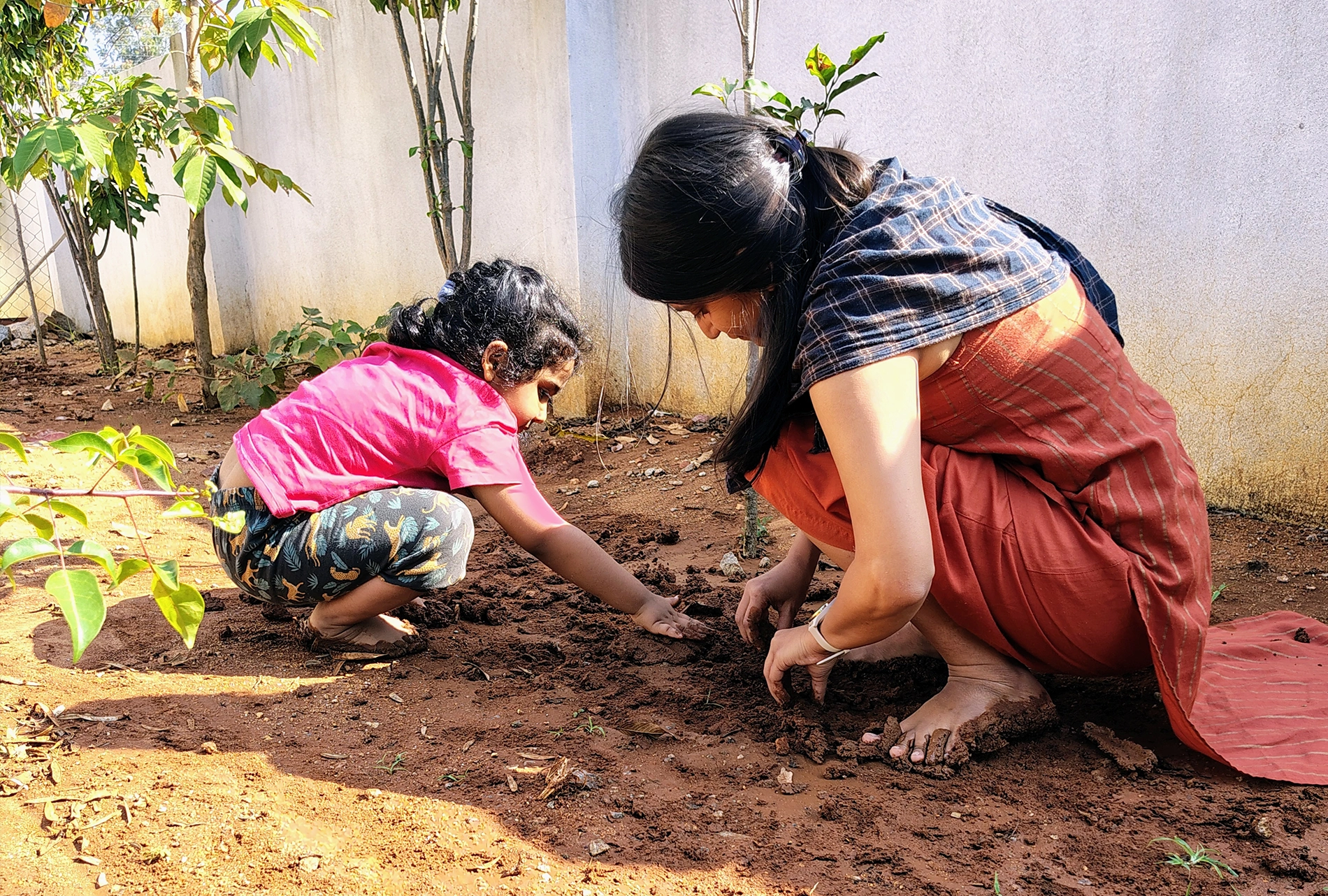 A teacher and child plant a sapling together