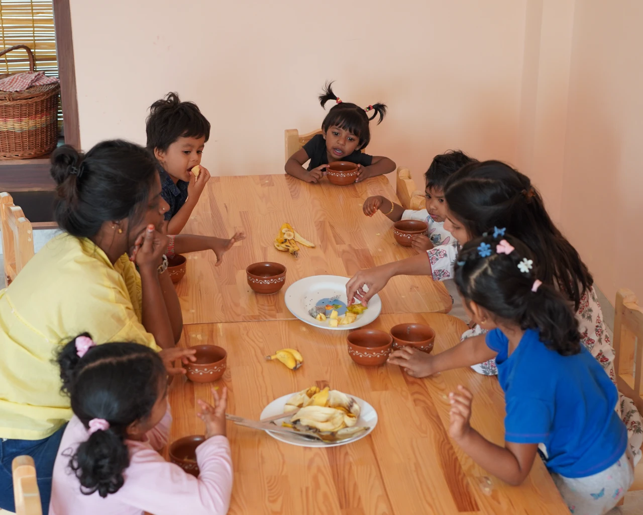 Children share lunch at a low wooden table