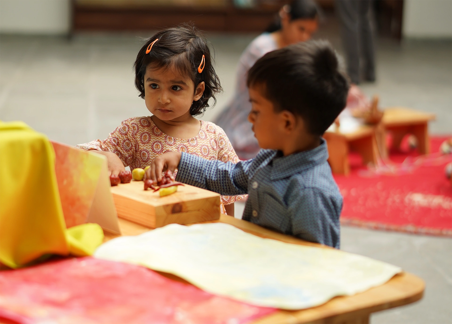 Two young children work side by side at a low wooden table in a Thraya classroom